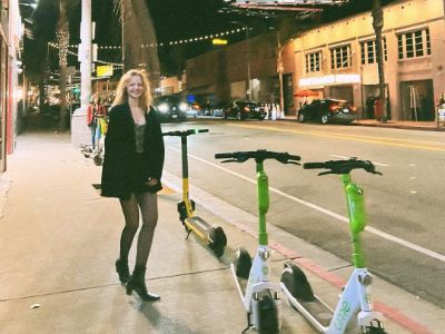 Emma Laird is posing in the pedestrian walk in an empty street in the night.